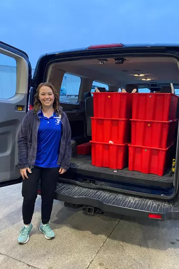 Feed-A-Child Coordinator standing next to van packed with meal bins