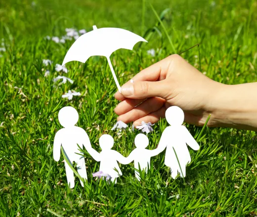 paper cut outs of four people with a human hand holding a paper cut out of an umbrella over them