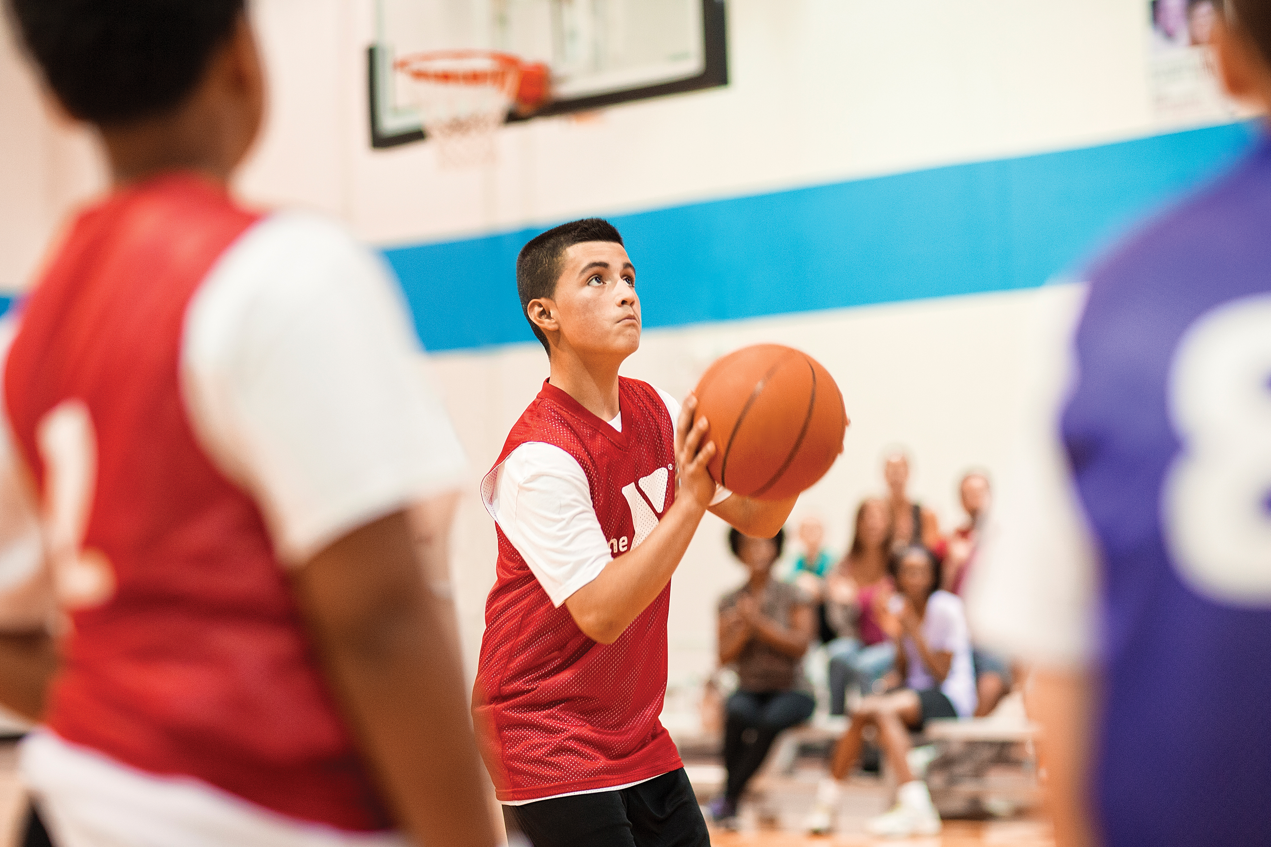 Boy shooting basketball with crowd in the background
