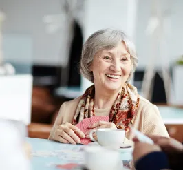 Smiling senior woman playing cards and enjoying coffee with friends