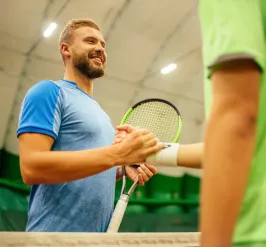 Smiling tennis player shaking hands across the net