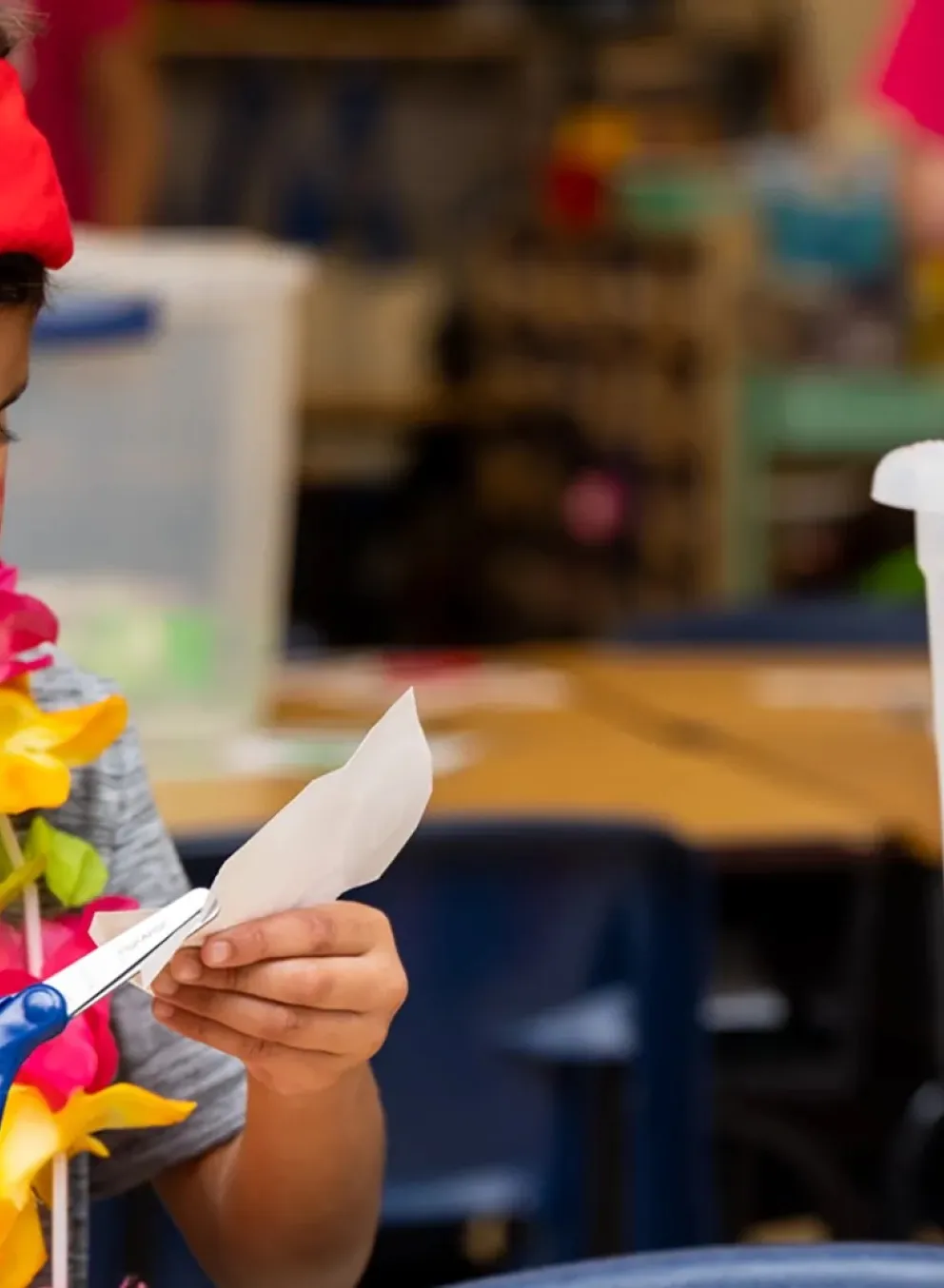 Child using scissors to craft during a challenge island class