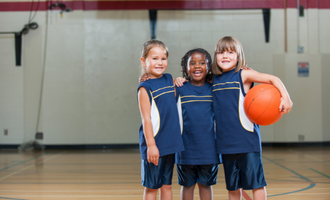 three children pose with a basketball 