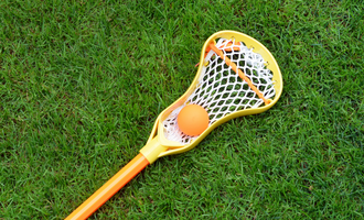 An image of a lacrosse stick on grass.