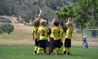 a group of little kids gather on a soccer field