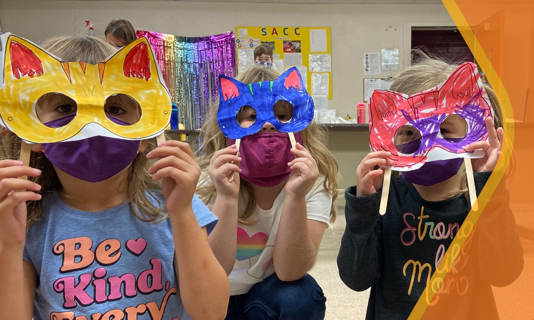 Three children with silly masks they made in SACC