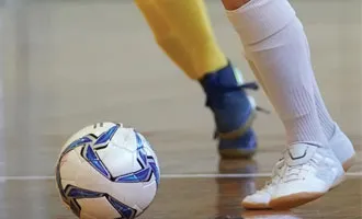 Men playing futsal soccer in Gym