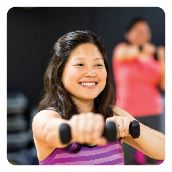 A woman holds weights in a group exercise class