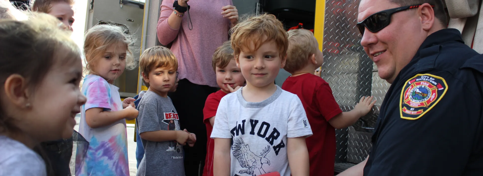 Children stand around a firefighter