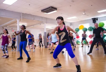 A diverse group of adults participate in a lively Zumba fitness class