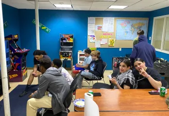 teens hanging out at teen center playing video games, watching sports, and smiling