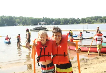 2 campers outside getting ready to go kayaking.
