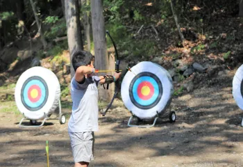 a camper at camp wells holds a bow and arrow and prepares to shoot 