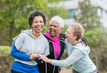 Three ladies laughing outside in workout clothes