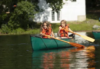 Two campers set off into the lake on their canoe.