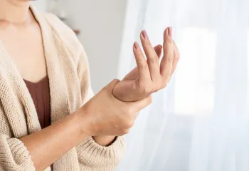 A person holding the base and wrist of their other hand