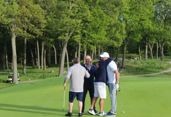 Golf foursome hugging on the green