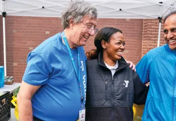 3 people smiling under a tent at the YMCA