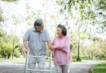 Older couple walking outside with walker