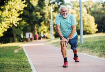 Older man stretching on a walk outside