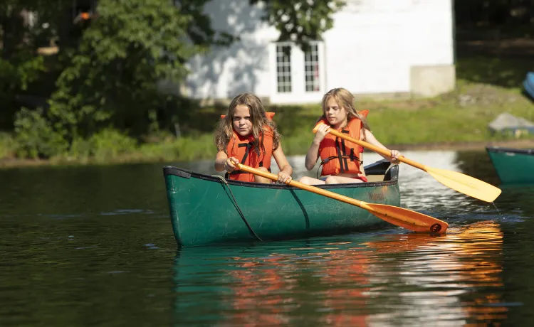 Two campers set off into the lake on their canoe.