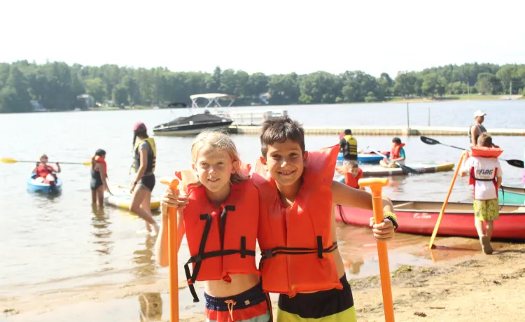 2 campers outside getting ready to go kayaking.