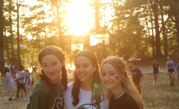 Three campers sand awaiting the closing ceremony as the sun begins to set. 