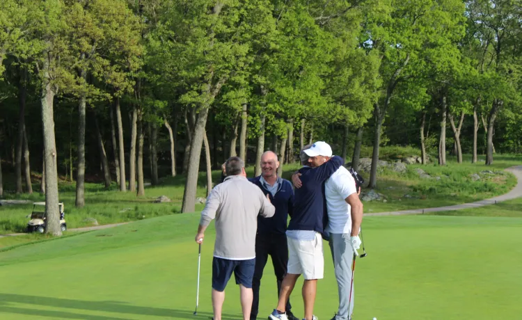 Golf foursome hugging on the green