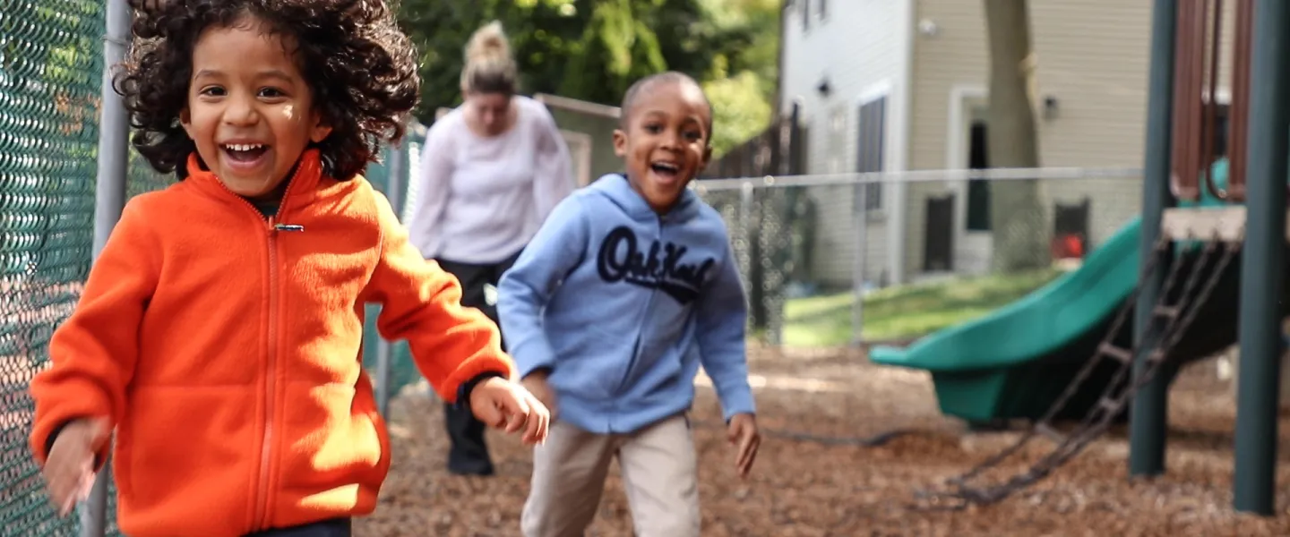 Two young children running happily around a playground