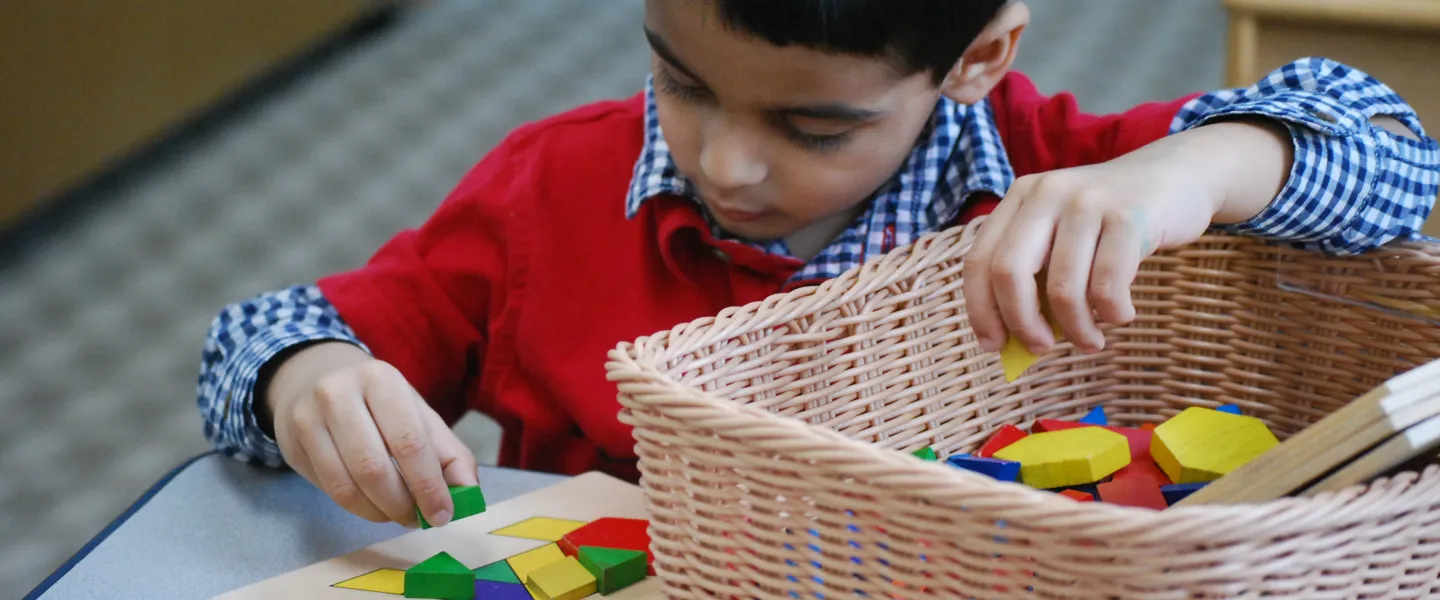 A preschool boy matches places colored blocks to match a pattern.