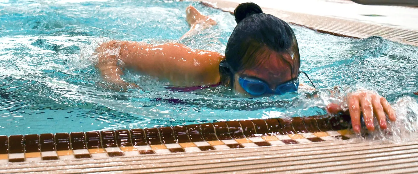 A woman practices her swim stroke in an indoor pool