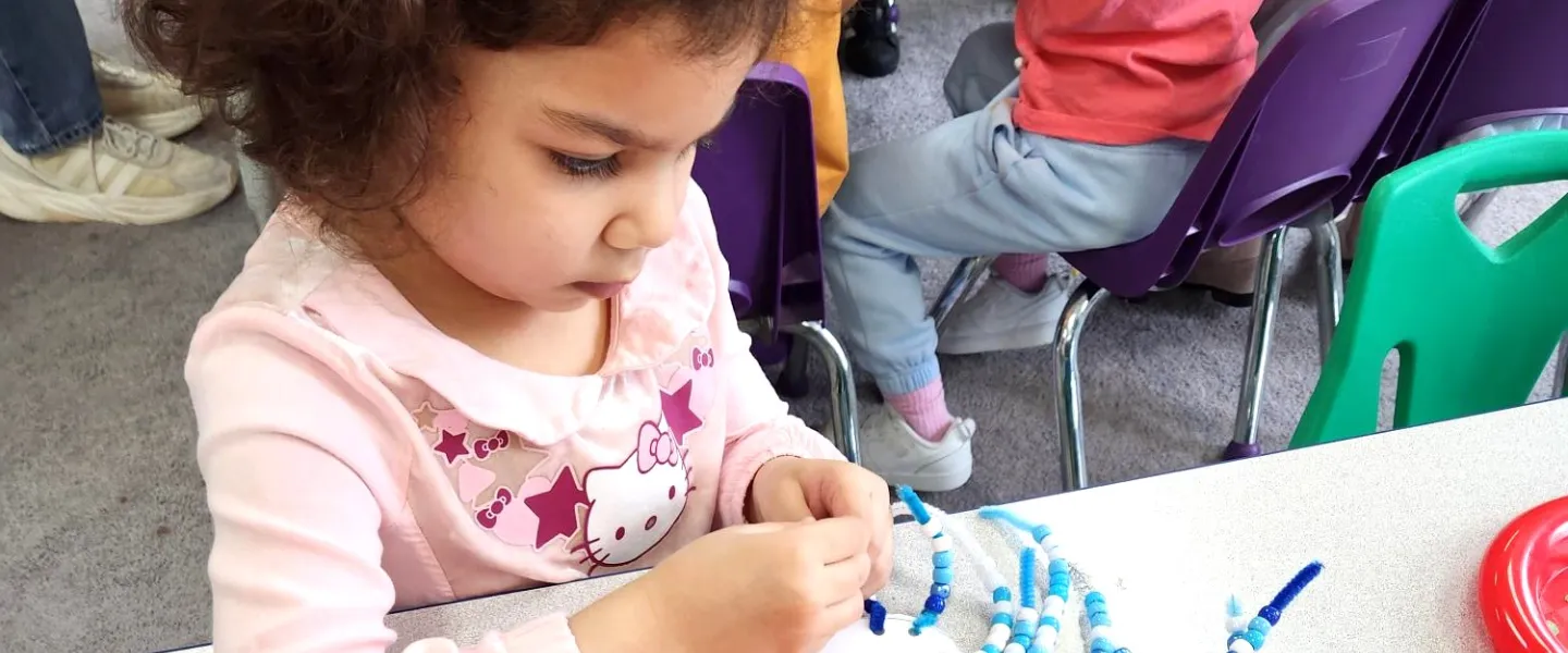 preschooler making bead project
