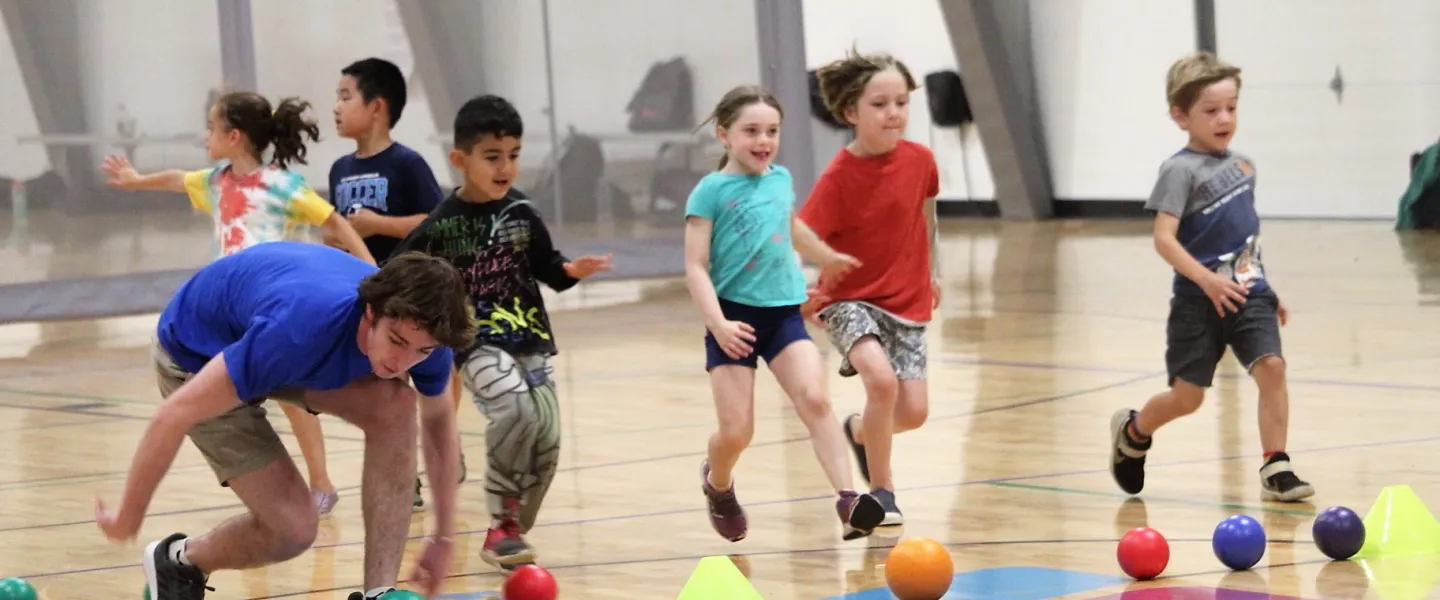 Campers at Camp Wells run for dodgeballs in the gym
