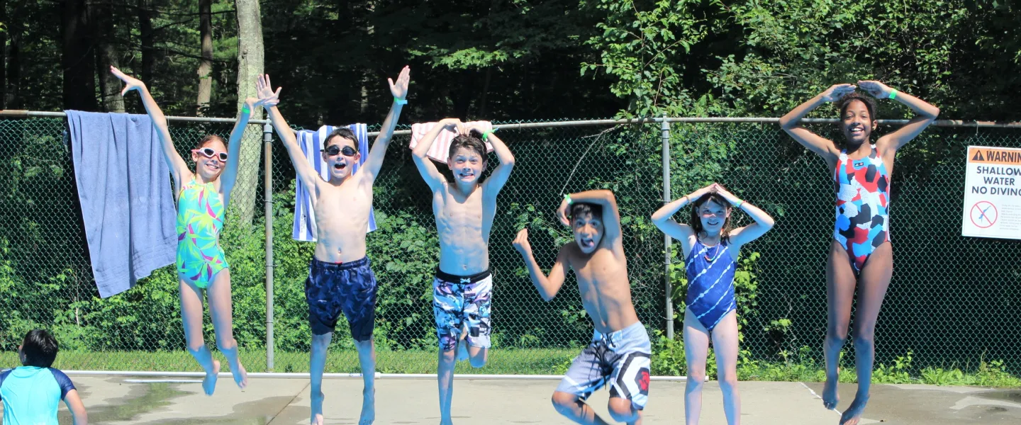 Campers attempt the YMCA arms while jumping into a pool