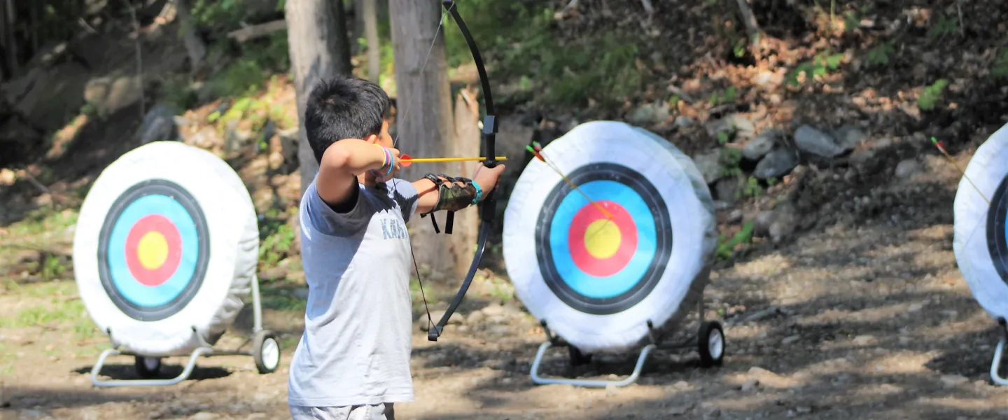 a camper at camp wells holds a bow and arrow and prepares to shoot 