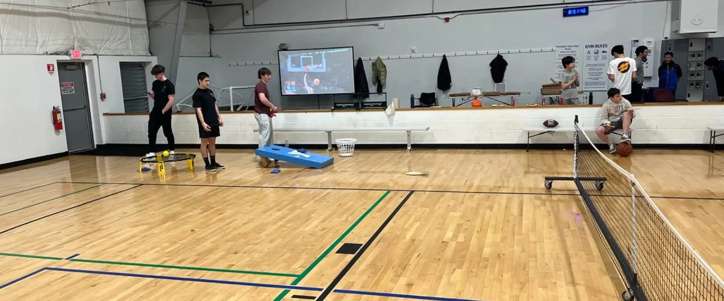 Teens playing cornhole at March Madness event