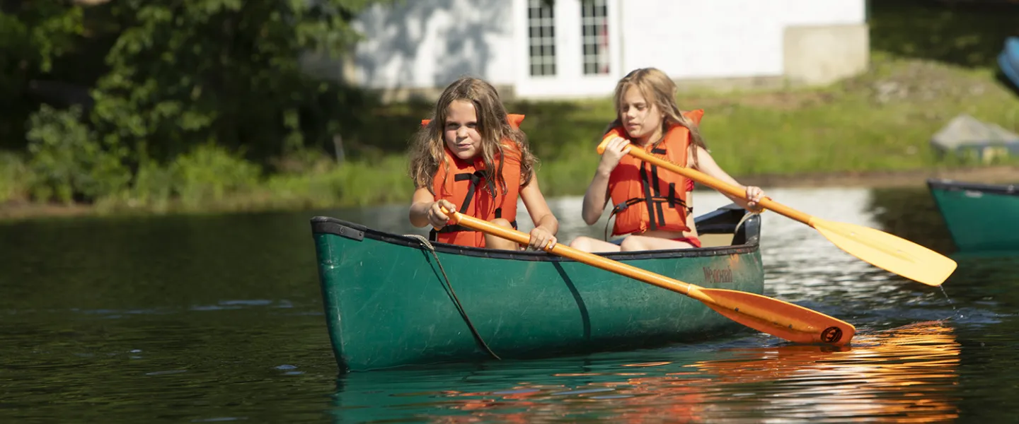 Two campers set off into the lake on their canoe.