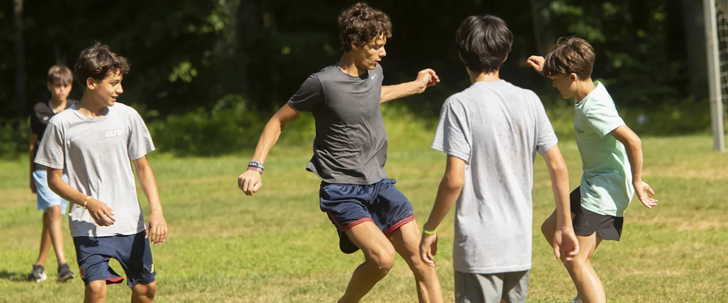 A couple of campers playing a game of soccer in the sun.