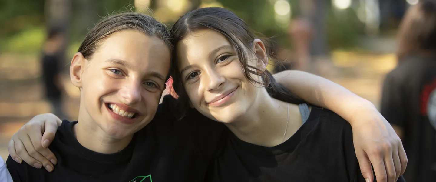 Two girl campers sitting together getting ready for the day to come to a close.