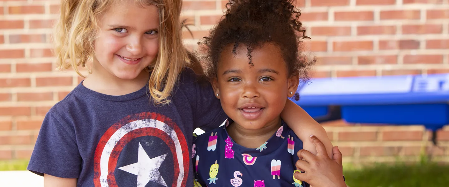 Two young camper friends standing outside together.