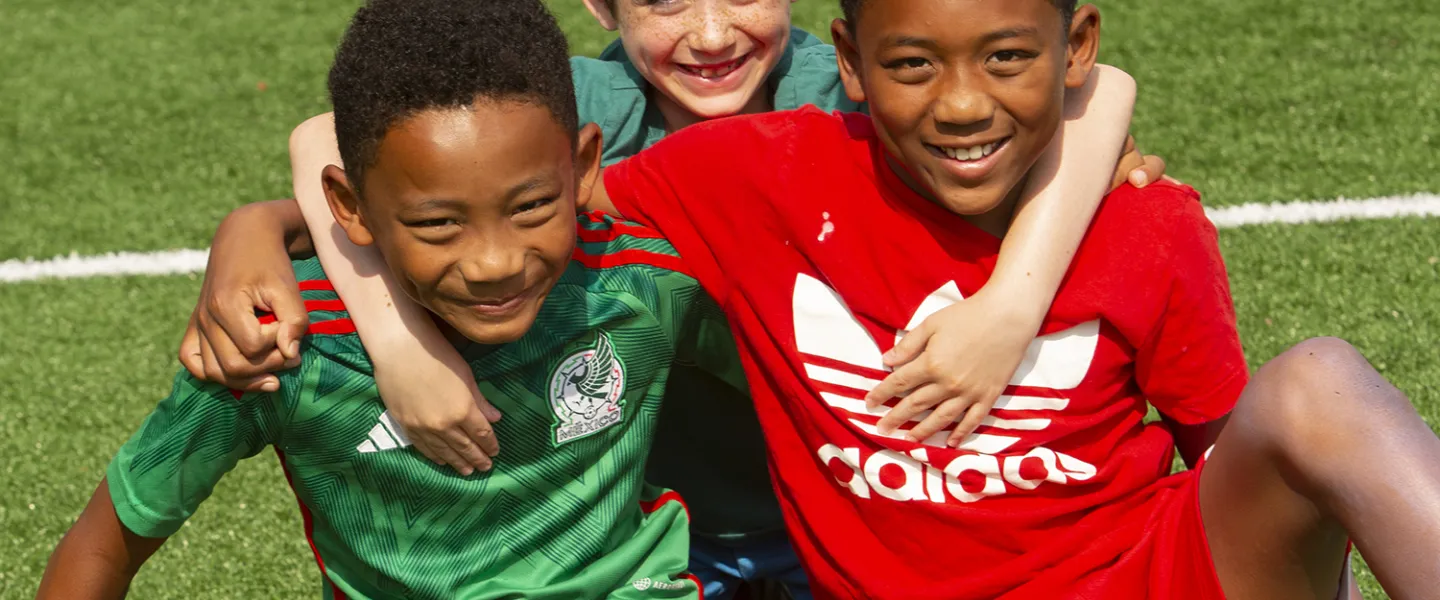 A couple friends sitting on the field after a soccer game.