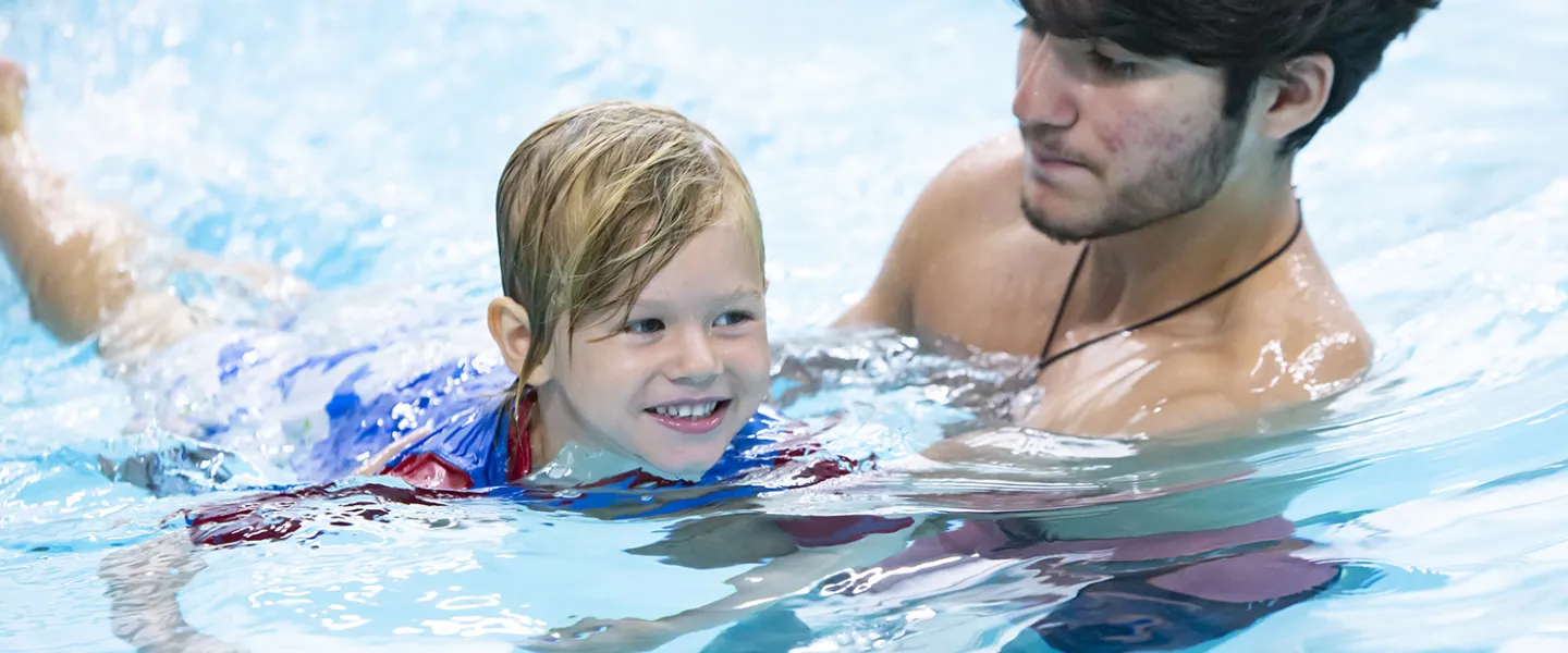 A consular helping his camper trying to teach him how to properly swim.