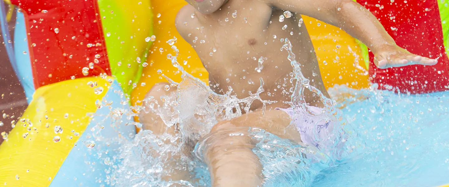 A young camper making a big splash down at the bottom of the slide.