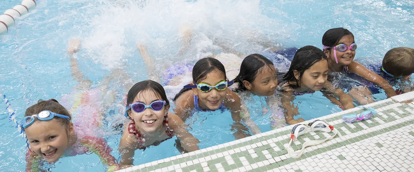 A group of seven campers show their consular how fast they can kick in the pool.