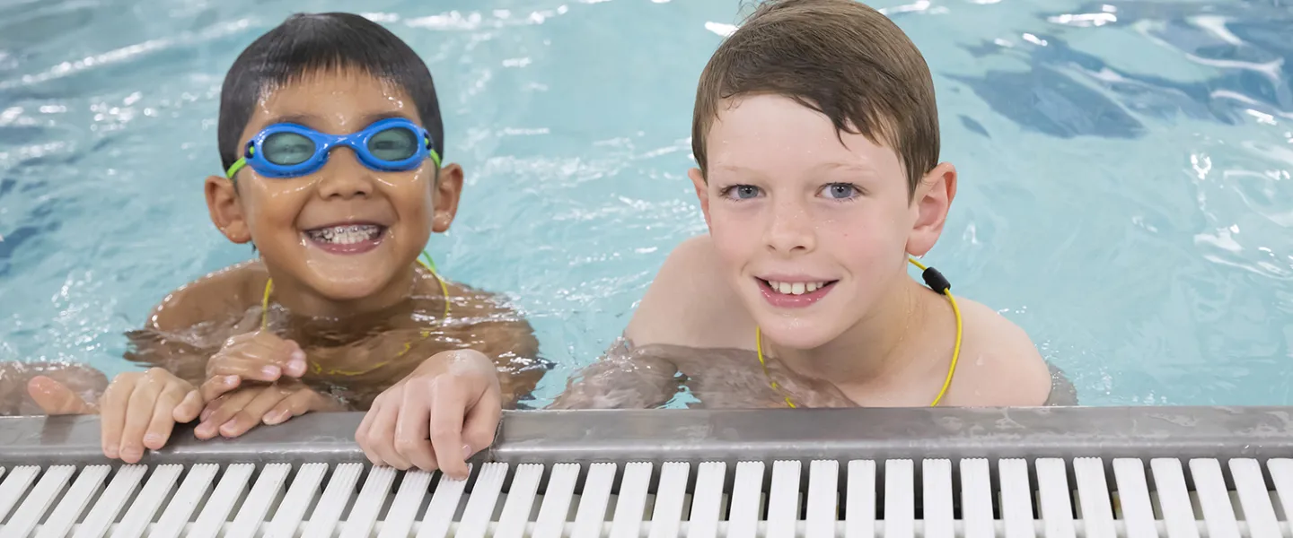 Two campers holding onto the edge of the pool.