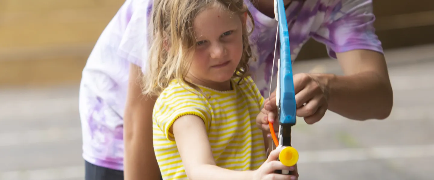 A consular showing his little camper how to use the bow n' arrow.