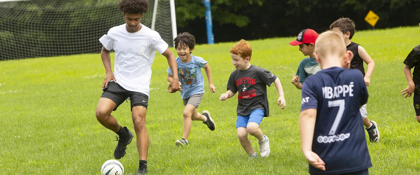 Campers chase after their consular to the soccer ball away.