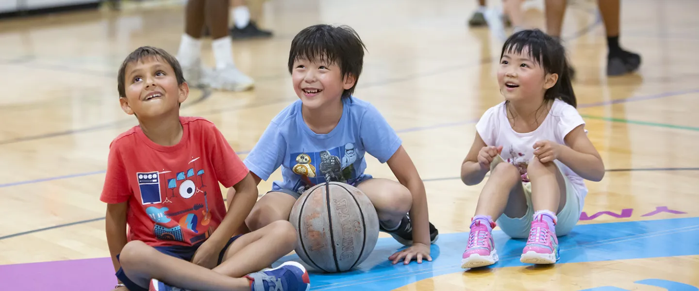 Three campers gathered in the basketball court entertained by their consular.