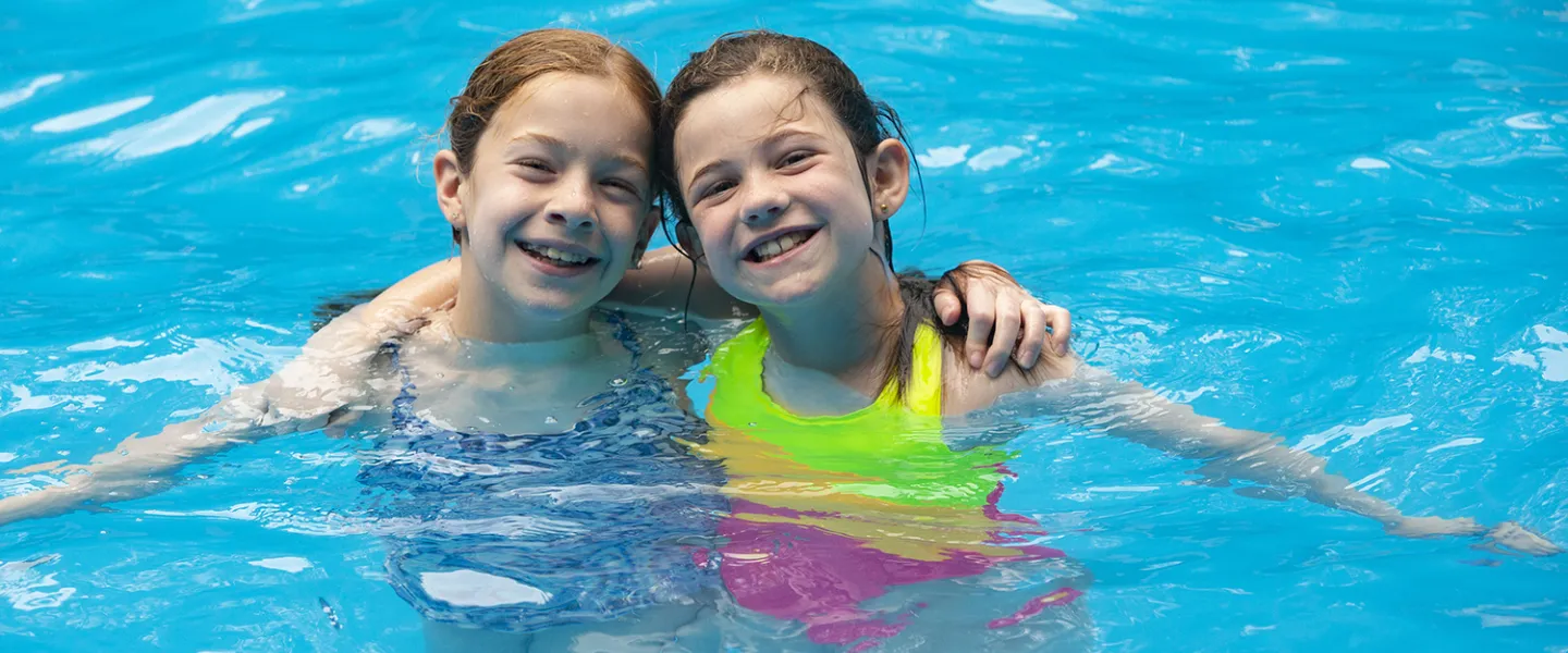 Two campers posing inside of the pool for the camera. 