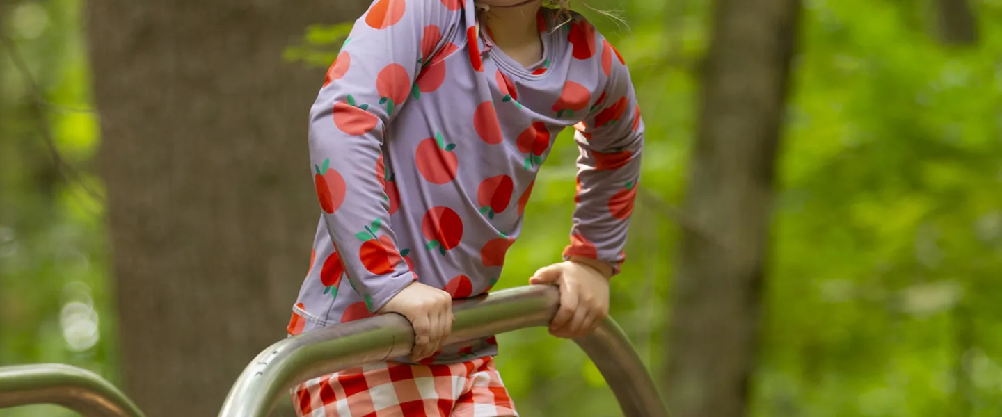 A young camper standing on part of a little jungle gym. 